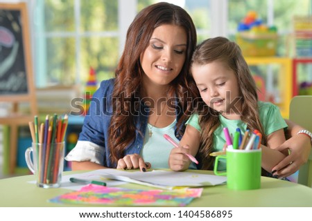 Portrait of mother and daughter drawing together with felt pens at playroom