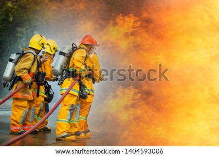Firefighters spraying high pressure water to fire with copy space, Big bonfire in training, Firefighter wearing a fire suit for safety under the danger case.