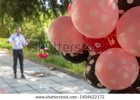 Performing of a magician through an outdoor birthday party with balloons.