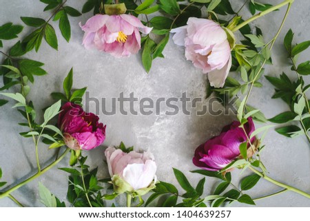Floral flat lay arrangement with pink and purple peonies on a grey table. Space for your text or products.