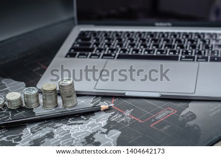 Arrange 5 coins in ascending order. Black wooden pencil And notebook computers on a black background.