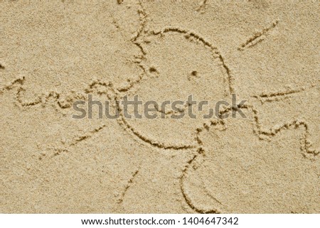 sun and clouds written on sand sand top view