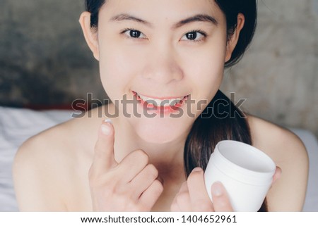 Portrait of young Asian woman applying acne cream/moisturizer on her face. Conceptual of beauty and cosmetic.
