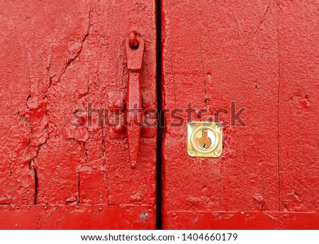 Iron knocker and lock in the old entrance door of house, Spain. Red background