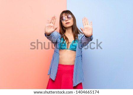 Young woman in bikini making stop gesture for disappointed with an opinion