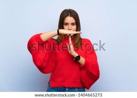 Young woman over isolated blue wall making time out gesture
