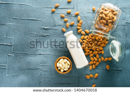 Almond milk in a glass with the ingredient on a dark concrete background