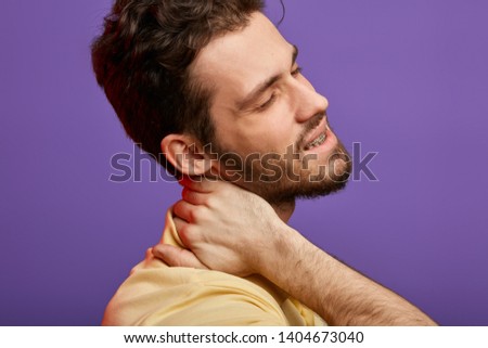 man has cervical rediculopathy. close up cropped photo.whisplash, sudden jolt to the neck . cancer concept. bearded pleasant man massaging his neck.