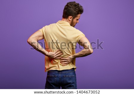 young man suffering from backache. close up back view photo. studio shot.disk herniation, slipped disk