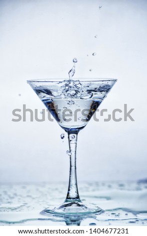 Martini glass with frozen splashing drops of drink - motion frozen close-up picture isolated on the white background.