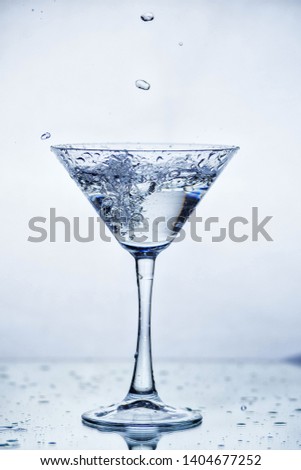 Martini glass with frozen splashing drops of drink - motion frozen close-up picture isolated on the white background.