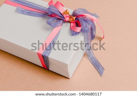 Gift box tied with blue and pink ribbons on pink background