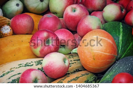 A variety of vegetables and fruits : pumpkin, zucchini, potatoes, apples, offered for sale at the fair.