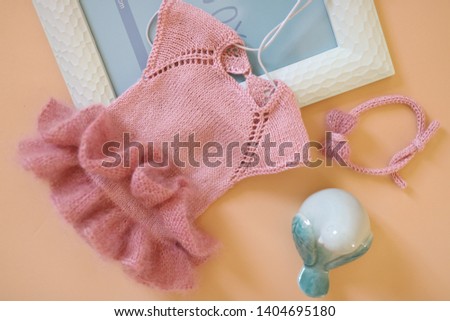 knitted dress for baby dusty rose color with a bow on a beige background with a picture and a bird