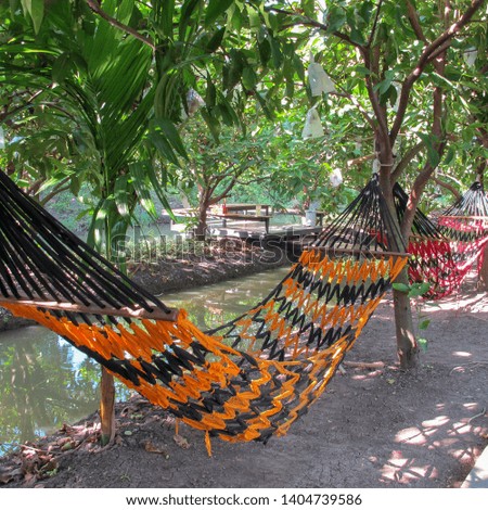 Hand-crafted hammocks hanging in the garden with a canal to relax                           