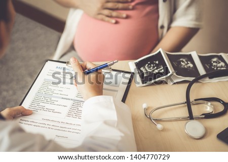 Happy pregnant woman visit gynecologist doctor at hospital or medical clinic for pregnancy consultant. Doctor examine pregnant belly for baby and mother healthcare check up. Gynecology concept. Royalty-Free Stock Photo #1404770729