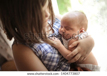 Older sister with a baby for 1 month, a girl hugging a newborn baby. Sibling care and love concept
