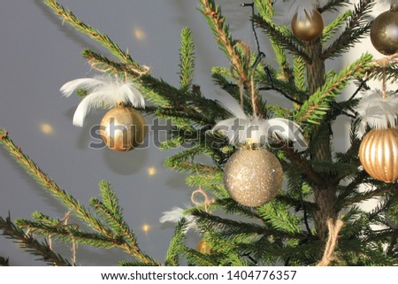 real decorated christmas pine tree with golden glitter toys and white feathers