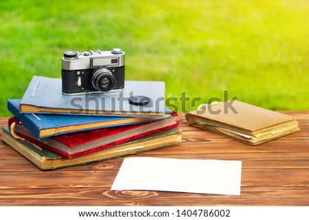 Old photo album with photos on a beautiful brown wooden table on the background of nature and old cameras.Copy space.Mockup free.