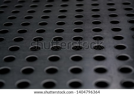 Gray monophonic background with big quantity of holes in a metal plate. Surface. Texture