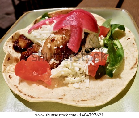 Mexican food concept : Grilled fish taco in green ceramic plate on wooden table