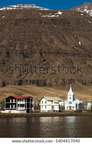 View to the small town and snowy mountains in the fjord of Iceland.