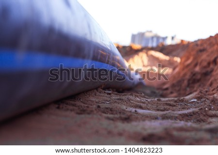 Plastic water pipe lay in a trench in the direction of residential buildings Copy space Royalty-Free Stock Photo #1404823223