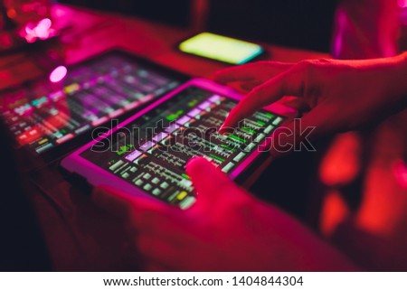 studio working with sound and light mixer console,hands of sound engineer working on recording studio mixer adjusting the volume of a sound mixer audio mixing console with digital mixer tablets.