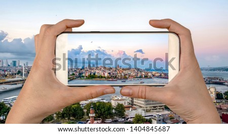 Tourist taking a picture in front of 
 Golden Horn against Galata tower, Istanbul, Turkey 