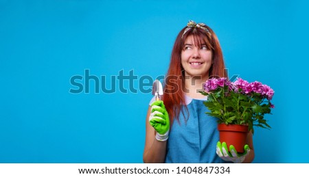 Photo of happy brunette with pot of chrysanthemums and an iron shovel