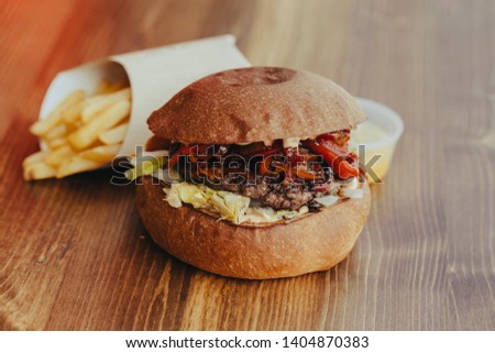 Fresh tasty burger and french fries on wooden table 