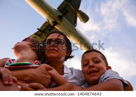 A passenger plane flies low above the head of a woman with two children. Exciting adventure on summer vacation.Exciting adventure and incredible experience.
