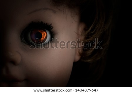 Close-up scary vintage doll face isolated on black background. Soft backlight, focus on eye. Halloween concept Royalty-Free Stock Photo #1404879647