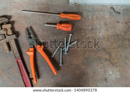 Old wooden workbench with metal tools over it. Screwdriver, wrench and pliers over the working table. Old rusty tools, plumber tools, vintage metal tools used on construction and repair.