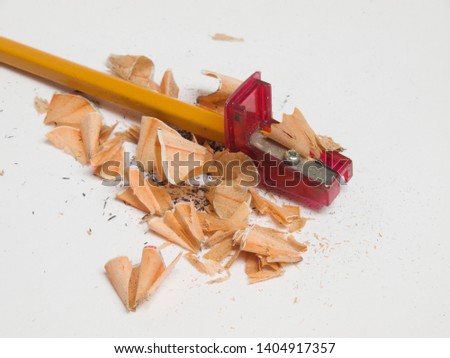Sharpened pencil with the sharpener and cutted wood residues and graphite, on the white background
