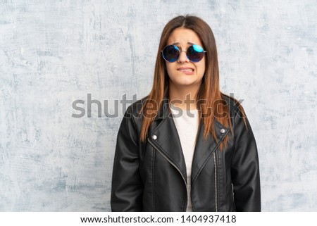 Young woman over textured wall having doubts and with confuse face expression