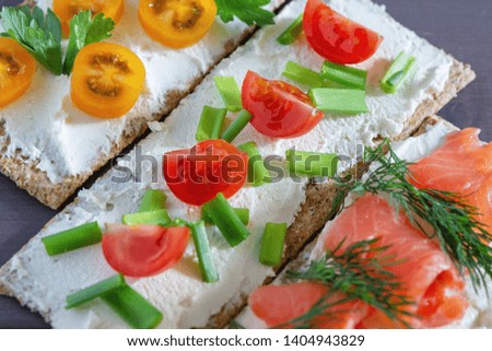 Crispbread with soft cheese, trout, tomatoes, dill and green onions, close-up. Light summer snack. Bright picture.