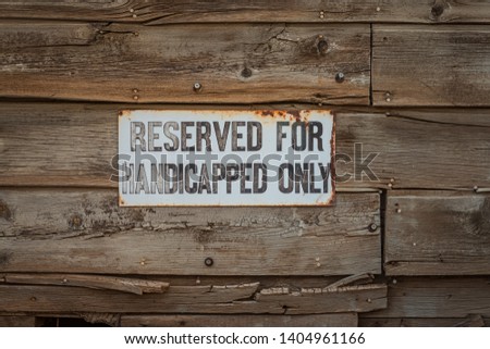 An old white sign for reserved handicap parking.