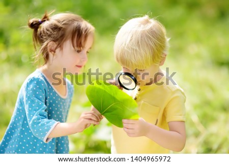 Kids exploring nature with magnifying glass. Close-up. Little boy and girl looking on leaf with magnifier. Summer activity for inquisitive child Royalty-Free Stock Photo #1404965972