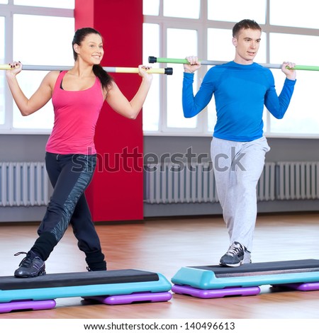 Young man and woman at the fitness gym is doing stretching exercises