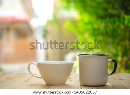 Cup of hot coffee on wooden table in the green garden morning. 

