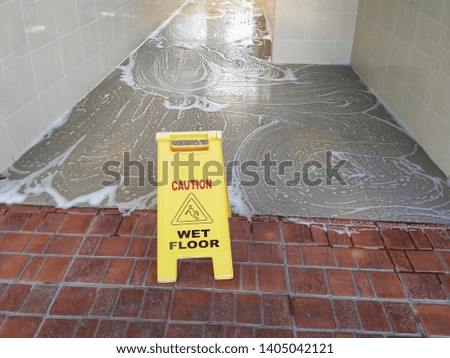 caution wet floor sign over wet floor with cleanser foam.