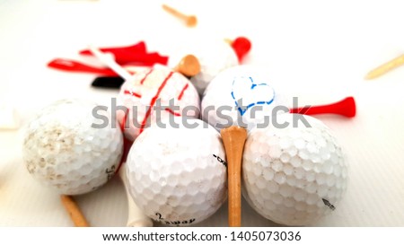 White golf balls. Picture of love heart on one golf ball as a romantic gesture for girlfriend. Tee pins spread around balls. Couple love.