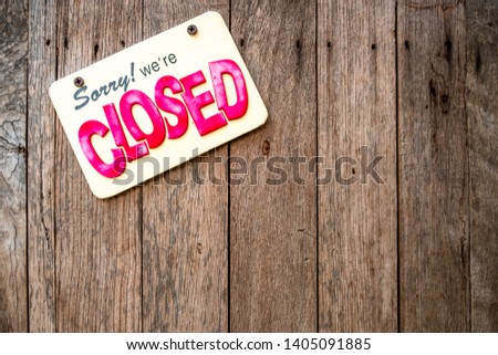 A 'Sorry We're Closed" sign with yellow background and red and black English texts attached to wooden door. Royalty-Free Stock Photo #1405091885