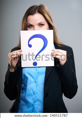 Attractive young woman in a black jacket. Woman holds a poster with a big question mark. Poster covers her face. On a gray background