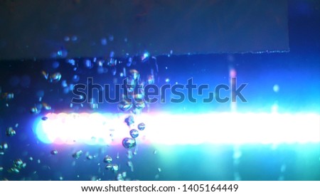 Side view of beautiful chaotic motion of oxygen bubbles, water background. Frame. Empty glass tank with water and bright blue lamp on the background.