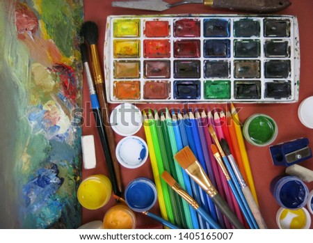   Set of watercolor with colored pencils and  palette and brushes, different art supplies background                           