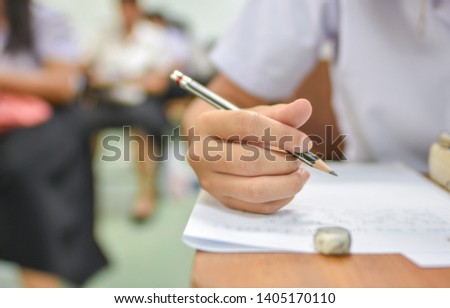 Hand holding pencil in the classroom activity; education concept photography or picture of student taking lecture note or doing the writing test in the training session of professional development 