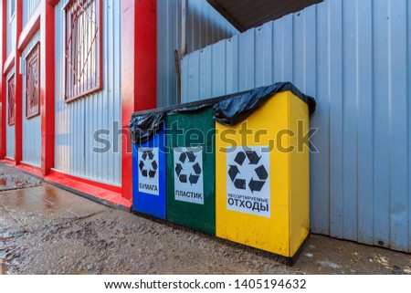 Containers for separate waste collection.  Translation: "Plastic, Glass, Paper, Unsorted."Trash bins for separate garbage collection site near iron fence and construction cabins. trash container. 