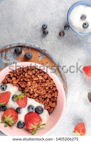 Bowl of homemade granola with yogurt and fresh berries on stone background from top view